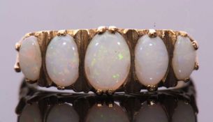 9ct gold five stone opal ring featuring oval graduated cabochon opals all in a pierced scroll