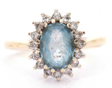 Light blue stone and diamond cluster ring, the oval shaped stone multiclaw set and raised above a