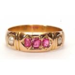 An antique ruby and seed pearl ring centering three graduated rubies between two small seed