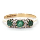 9ct gold emerald and diamond ring, the design featuring three small round cut emeralds highlighted