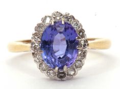 Tanzanite and diamond cluster ring, the oval faceted tanzanite 14 x 8mm raised within a small single