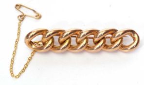 Yellow metal curb link style brooch, a design featuring six entwined links, 55mm long, tested for