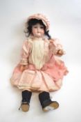 Early 20th Century doll, the bisque head marked EM6 in pink dress with glass eyes, 60cm long