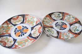 Two Japanese porcelain chargers with polychrome designs of island scenes and flowers, largest 40cm