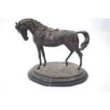 Spelter model of a racehorse on oval base mounted on a black marble type base, 30cm long