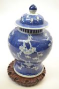 Chinese porcelain ginger jar and cover on carved wooden stand with prunus decoration on a blue