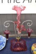 Large Cranberry glass epergne with three tapering stems and a pair of curled arms with baskets