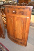 19th Century mahogany bow front corner cabinet with two arched doors opening to a shelved interior