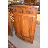 19th Century mahogany bow front corner cabinet with two arched doors opening to a shelved interior