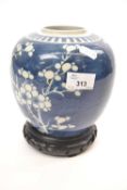 Chinese porcelain ginger jar, the blue ground decorated with prunus, the jar with carved wooden