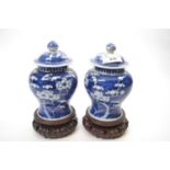 Two small Chinese porcelain jars and covers and wooden stands, the blue ground with prunus