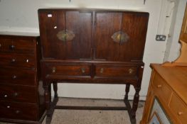 An early 20th Century oak side cabinet with four doors over two drawers raised on turned legs with