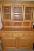 Modern light wood kitchen dresser with glazed top section over a base with three drawers and three