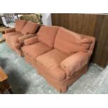 Pair of two seater, upholstered sofas, in a patterned salmon pink fabric, loose covers. Consigned