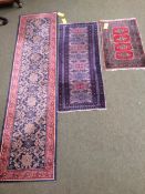 3 rugs: a runner with red border and blue and floral central panel, and 2 smaller red and blue