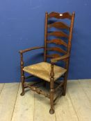An oak ladder back rush seated arm chair