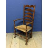 An oak ladder back rush seated arm chair