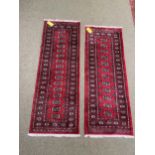 Two Pakistan Bokhara handknotted wool red ground rugs, with central panel of lozenge patterns, and