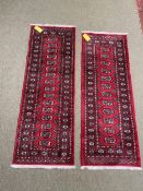 Two Pakistan Bokhara handknotted wool red ground rugs, with central panel of lozenge patterns, and