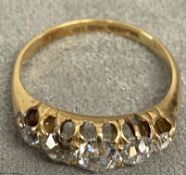 An 18ct gold and diamond five stone ring, set with graduated line of old cut diamonds in a scrolling
