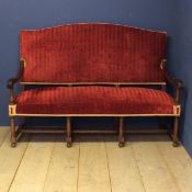 A good heavy oak framed hall settee with carved scrolling arms, and with red upholstered overstuffed