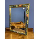 A decorative mirror with hand painted floral and gold coloured border