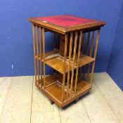 Small revolving light wood pedestal book case with red inset top 78h x 48 x 48cm