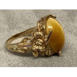 Yellow metal and Tigers eye ring marked 10k, central oval Tigers eye with cast and pierced