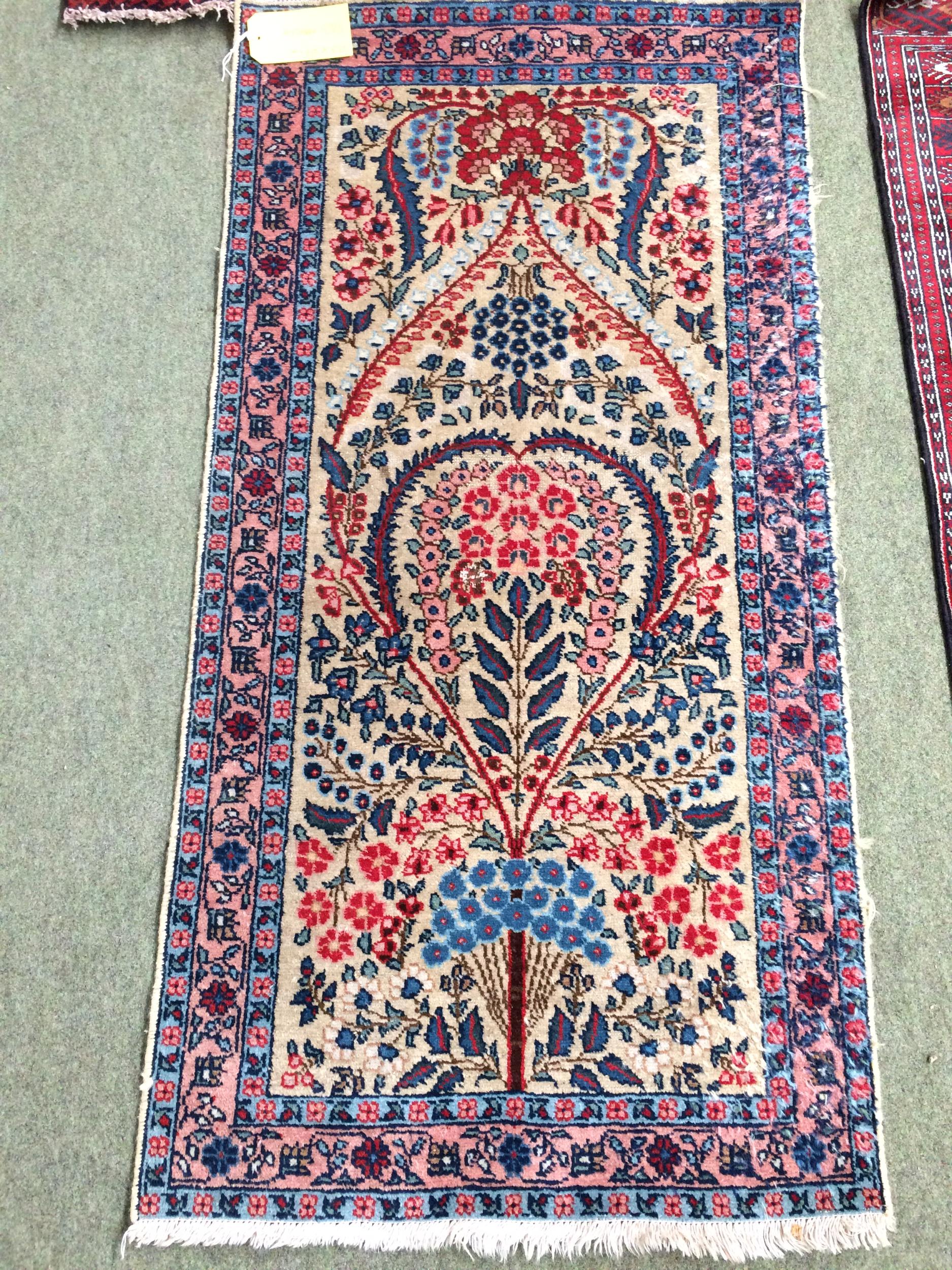 4 rugs, 3 red ground rugs with all over geometric stylized designs, and a blue and red ground Tree