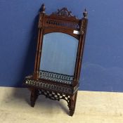 Mahogany hanging wall mirror and shelf, with ornately carved fretwork design and finials