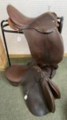A metal free standing saddle horse, and 2 leather saddles, see images for details and names