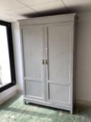 A decorative grey painted wardrobe, the two doors opening to reveal hanging rail on the left hand