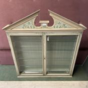 A Decorative, cream and floral painted narrow glazed cabinet, with glass shelves to the interior,