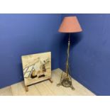 Brass standard lamp with pink shade, and an oak framed fire guard with tapestry panel of biblical