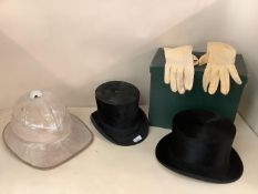 Two top hats, one in fitted green case, and a Pith helmet, all with wear