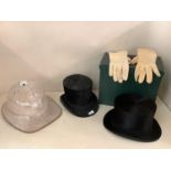 Two top hats, one in fitted green case, and a Pith helmet, all with wear