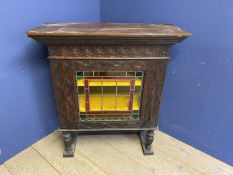 A profusely carved oak cabinet, with central lead and glazed panel