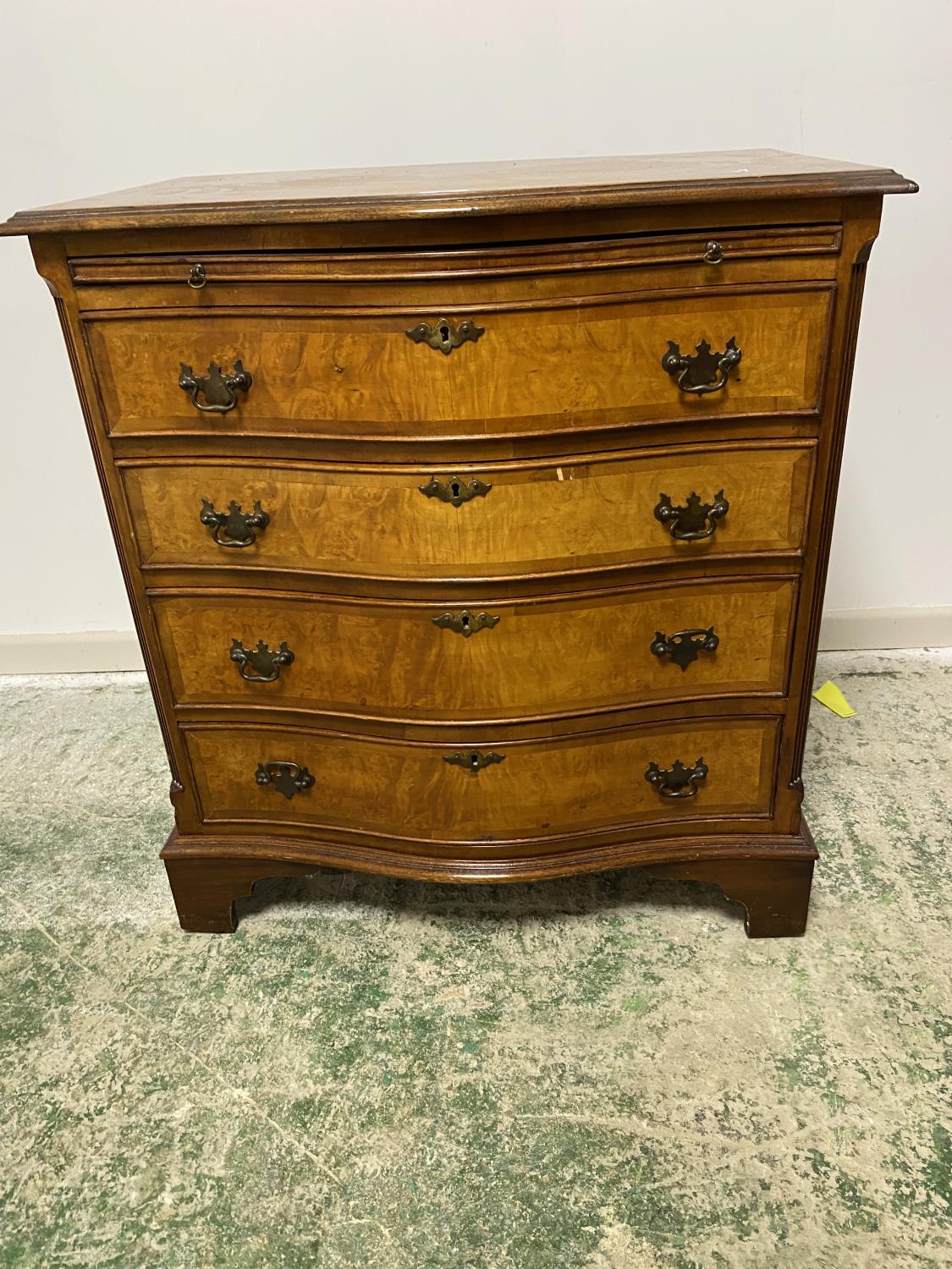 A modern, walnut veneered style, serpentine front chest of 4 drawers with brushing slide, some wear,