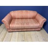 A pink upholstered settee, drop ends, 162cm Long