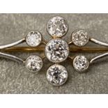 A Platinum and diamond bar brooch, old cut diamond in a colette setting with a surround of six old