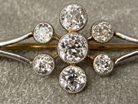 A Platinum and diamond bar brooch, old cut diamond in a colette setting with a surround of six old