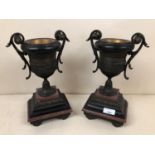 Pair of twin handled cast metal urns on stepped marble and onyx gilt bases