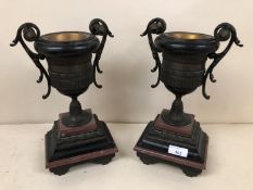 Pair of twin handled cast metal urns on stepped marble and onyx gilt bases