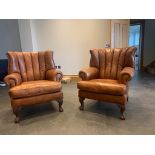 A pair of good tan leather club style arm chairs, with brass studded sides to the high backs, and