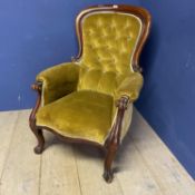 A large mustard coloured upholstered button backed show frame fireside chair