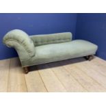 A green upholstered Victorian chaise longue with turned legs to castors