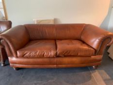 A good contemporary 2 seater tan leather sofa, with brass studded scrolling arms, and raised on