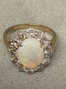 Opal and diamond 9ct gold flower ring. Central oval white opal in a four pronged setting in a