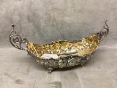 Silver boat shaped dish with scrolling handles chased decoration on 4 feet, marked to base, first