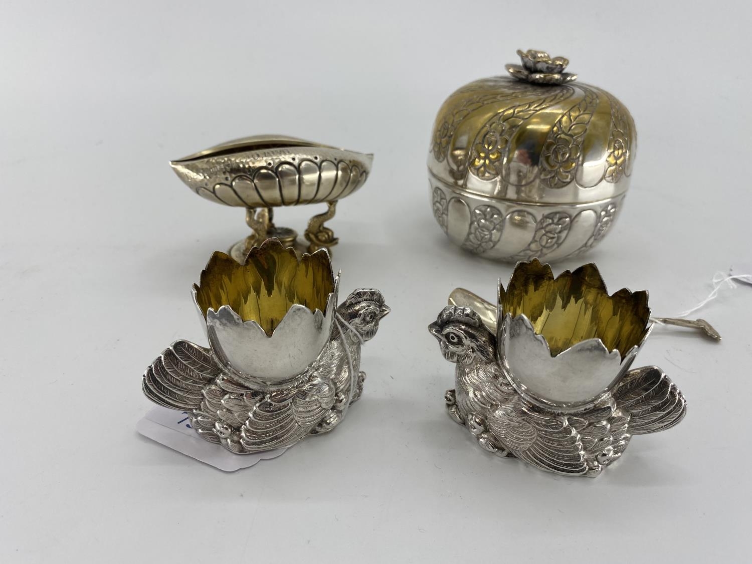 A pair of white metal egg cups in the form of cast chickens with gilt interiors, and a white metal